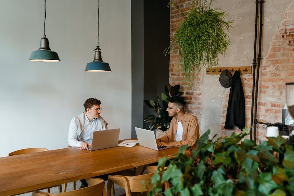 Woman in White Long Sleeve Shirt Sitting on Chair in Front of Macbook